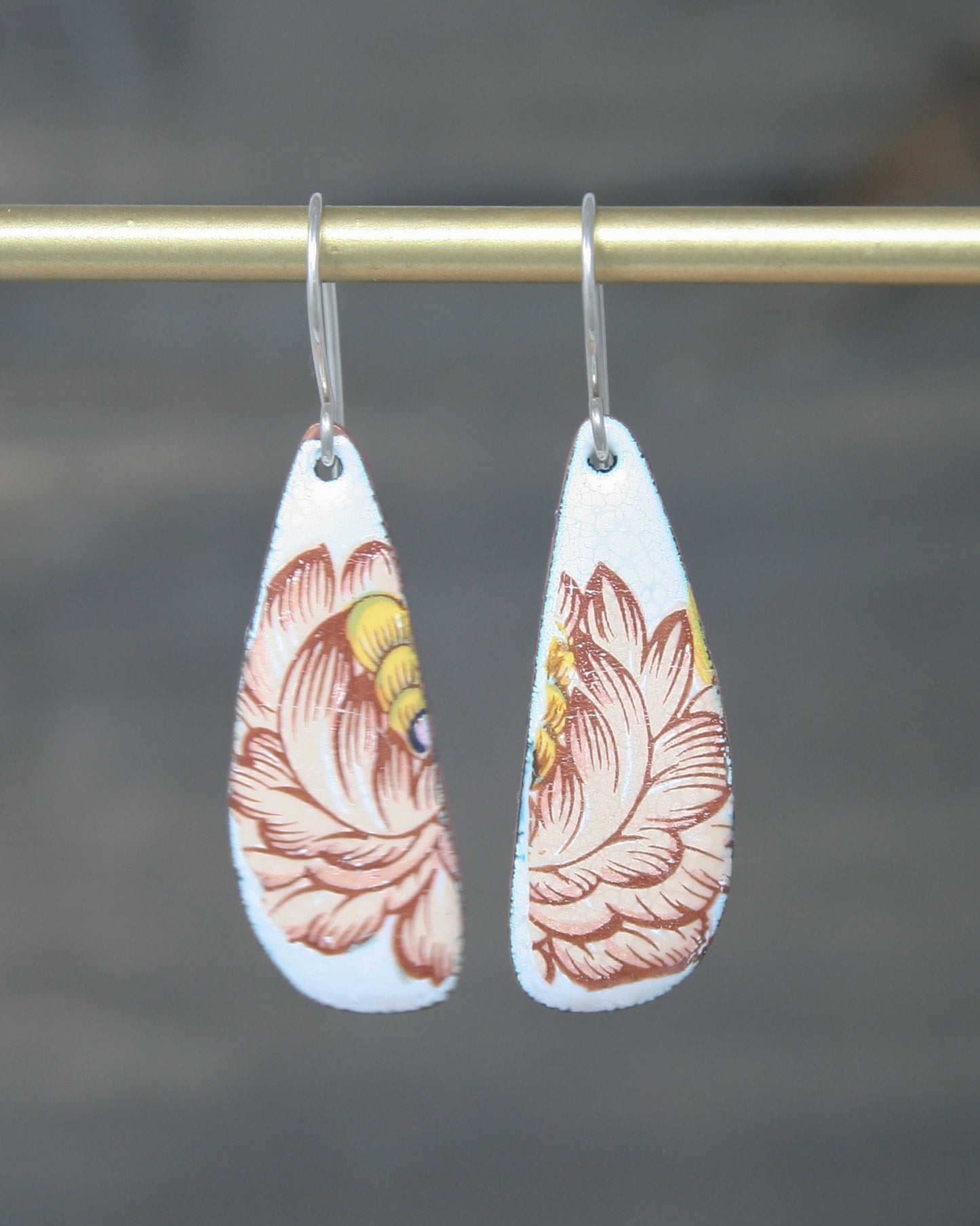 a pair of earrings with a flower painted on them