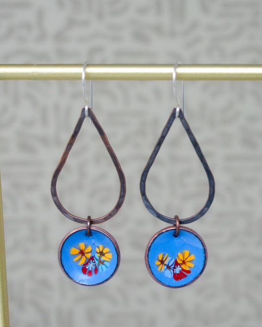 a pair of earrings with flowers painted on them