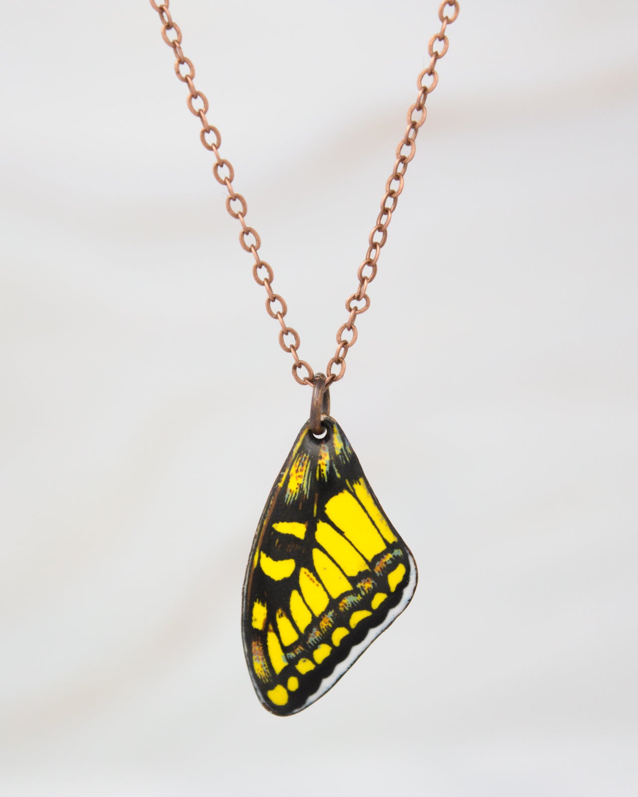 A necklace with a pendant featuring a yellow and black butterfly wing.