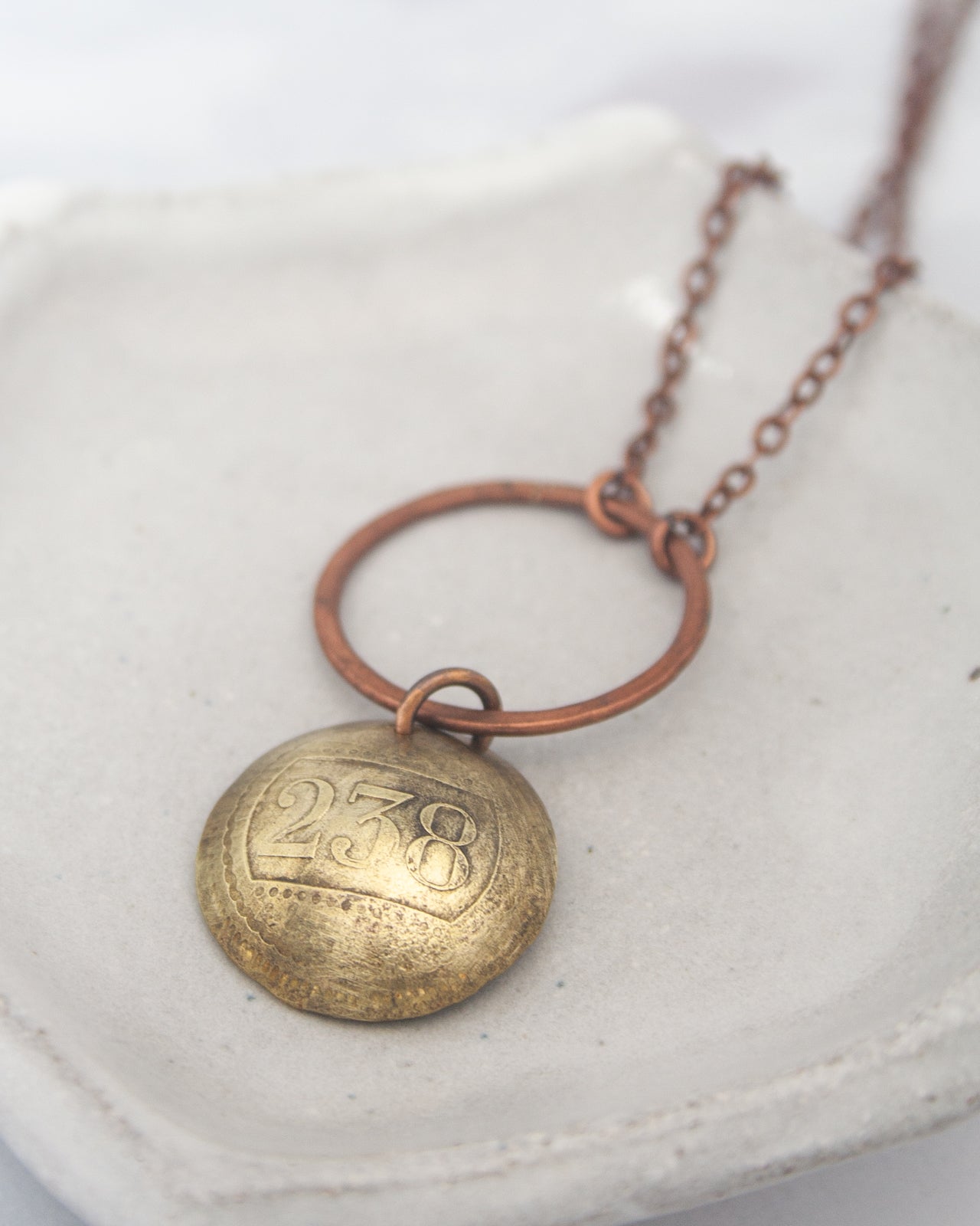 A necklace with a round metal pendant featuring the number "258" engraved on it.