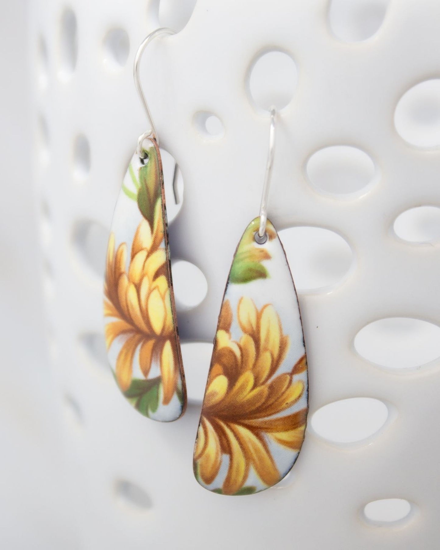A pair of earrings with a floral design, featuring yellow and green colors.