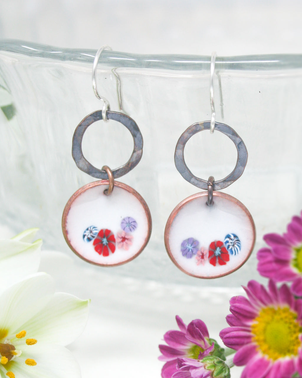 a pair of earrings with flowers painted on them