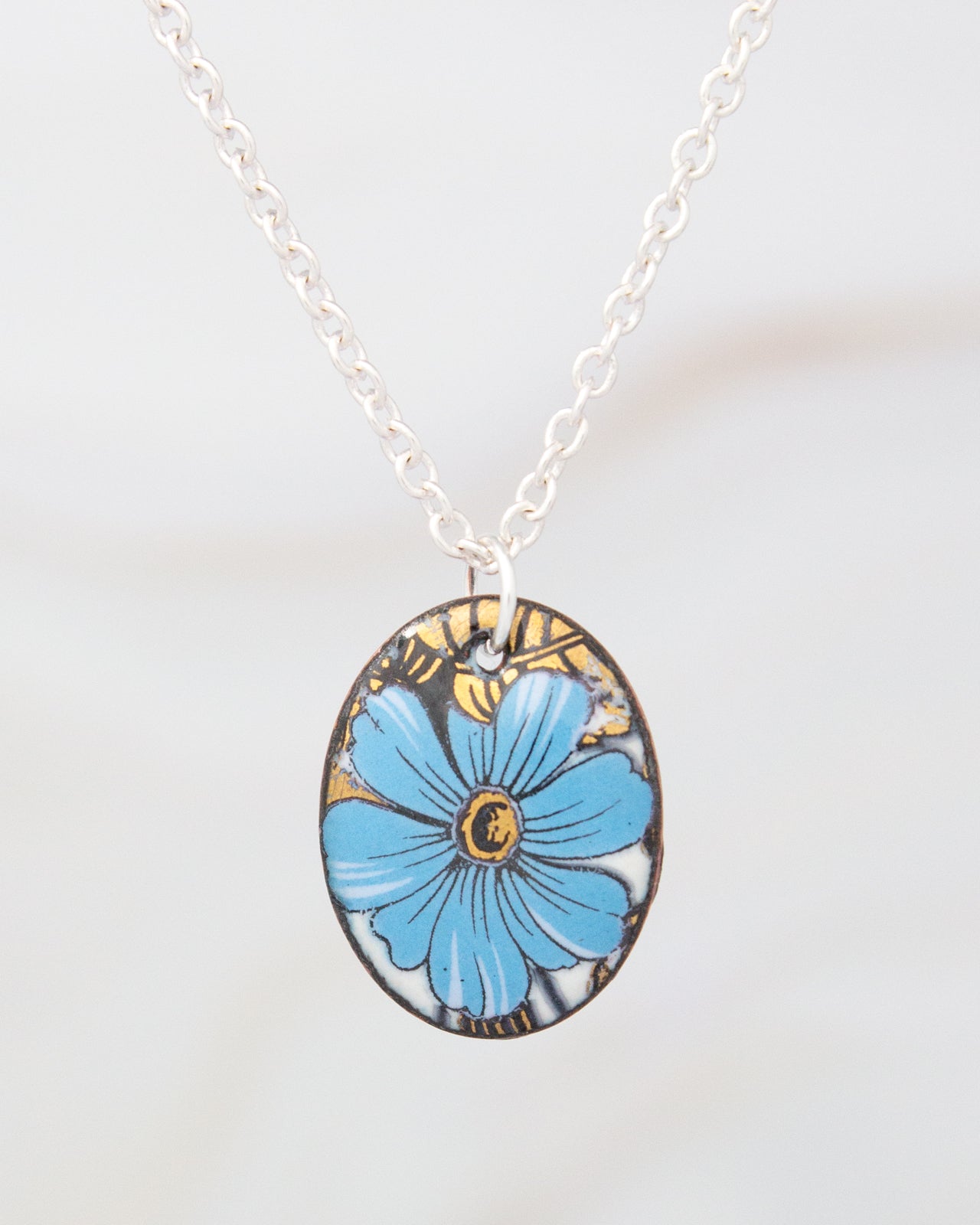 A necklace with a pendant featuring a blue flower design.