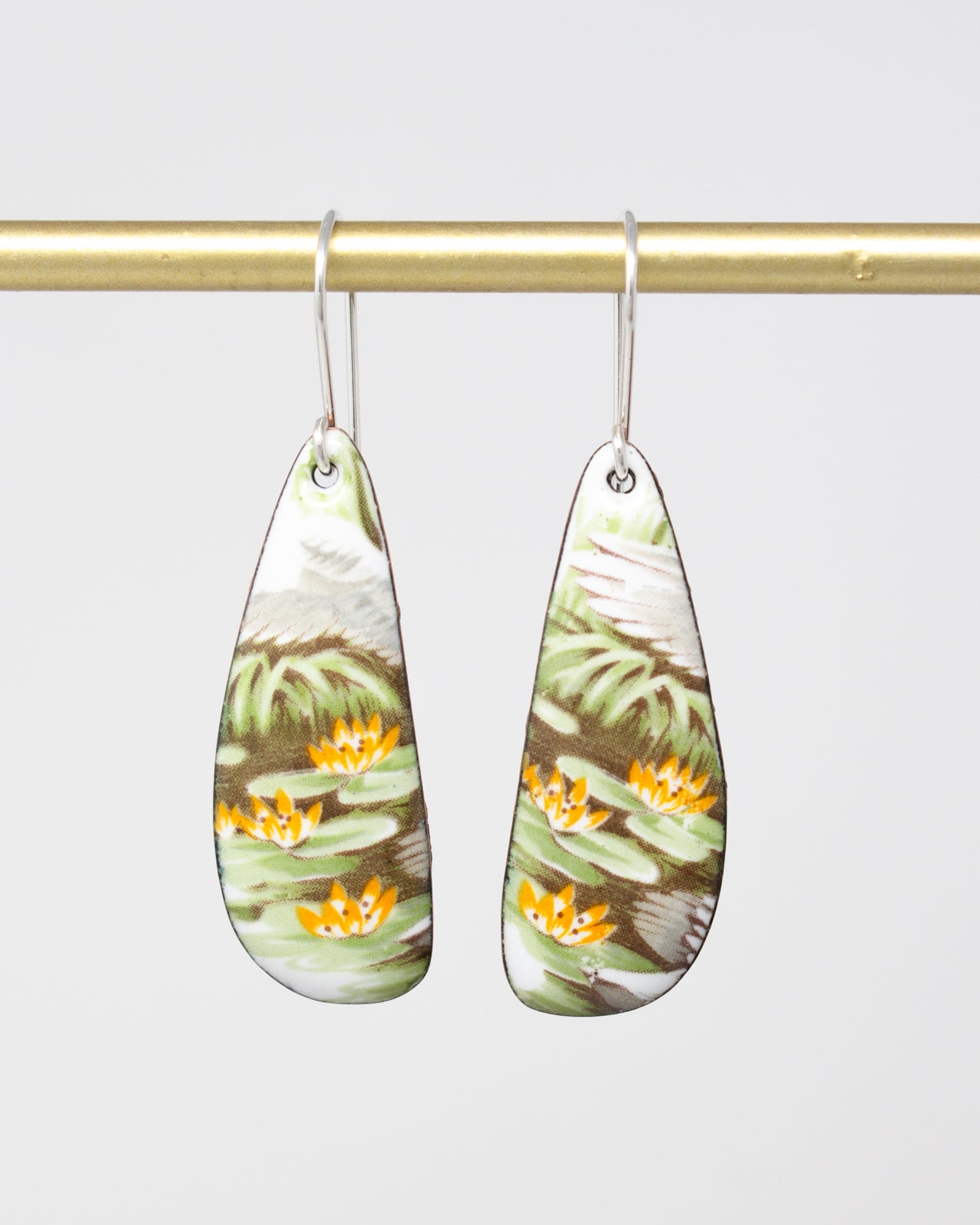 A pair of earrings with a floral design, featuring green and yellow flowers on a white background.