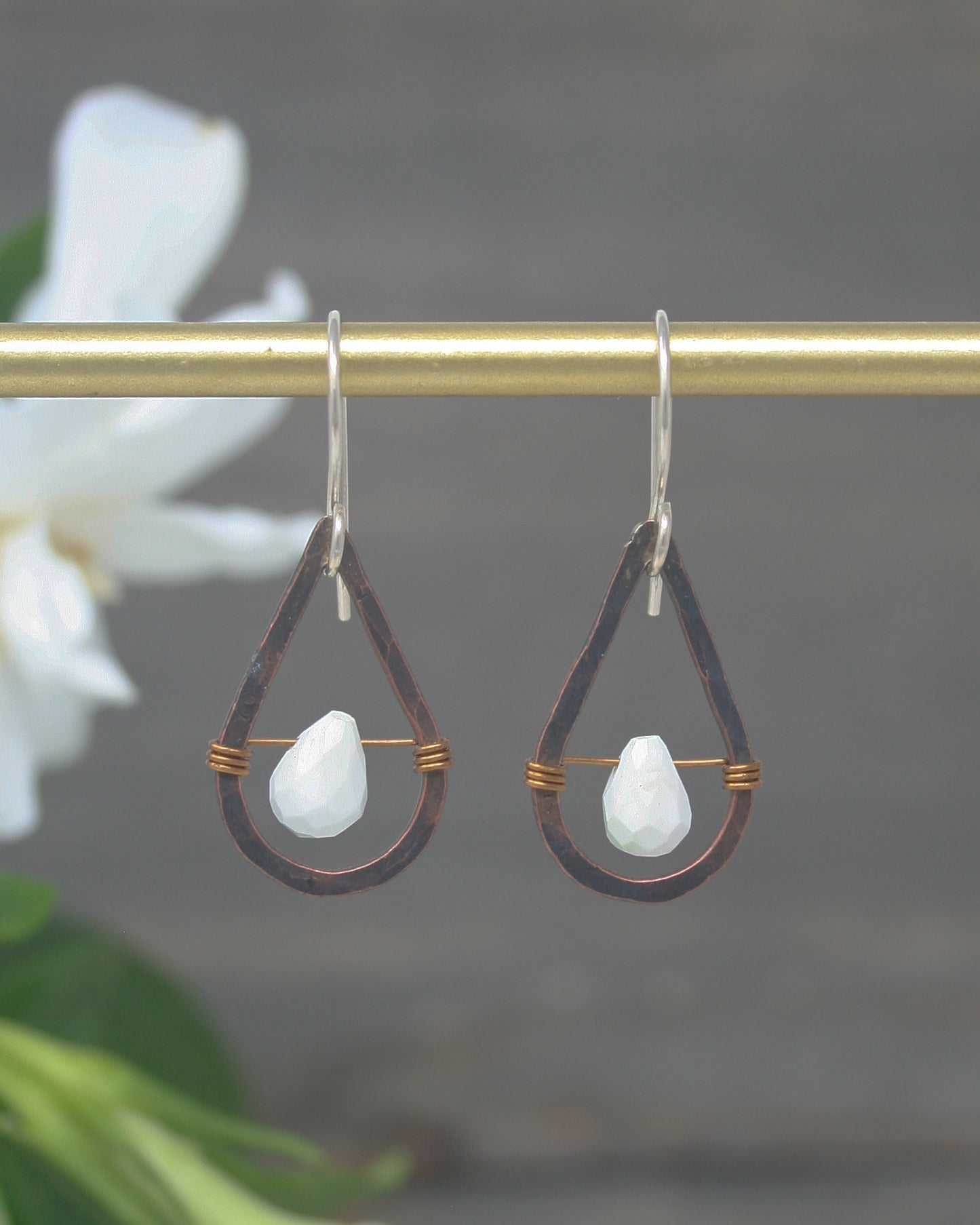a pair of earrings hanging from a metal bar