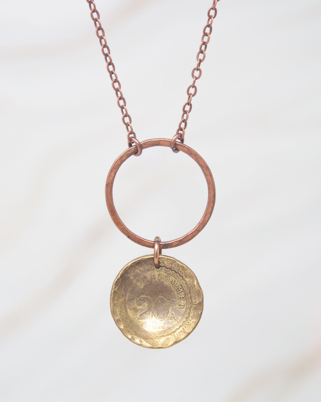 A necklace with a circular pendant featuring a coin design.