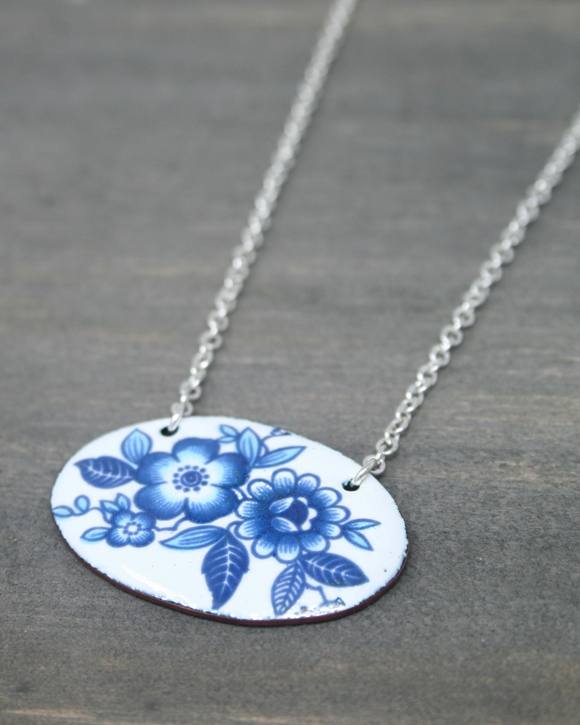 a blue and white flowered necklace on a silver chain