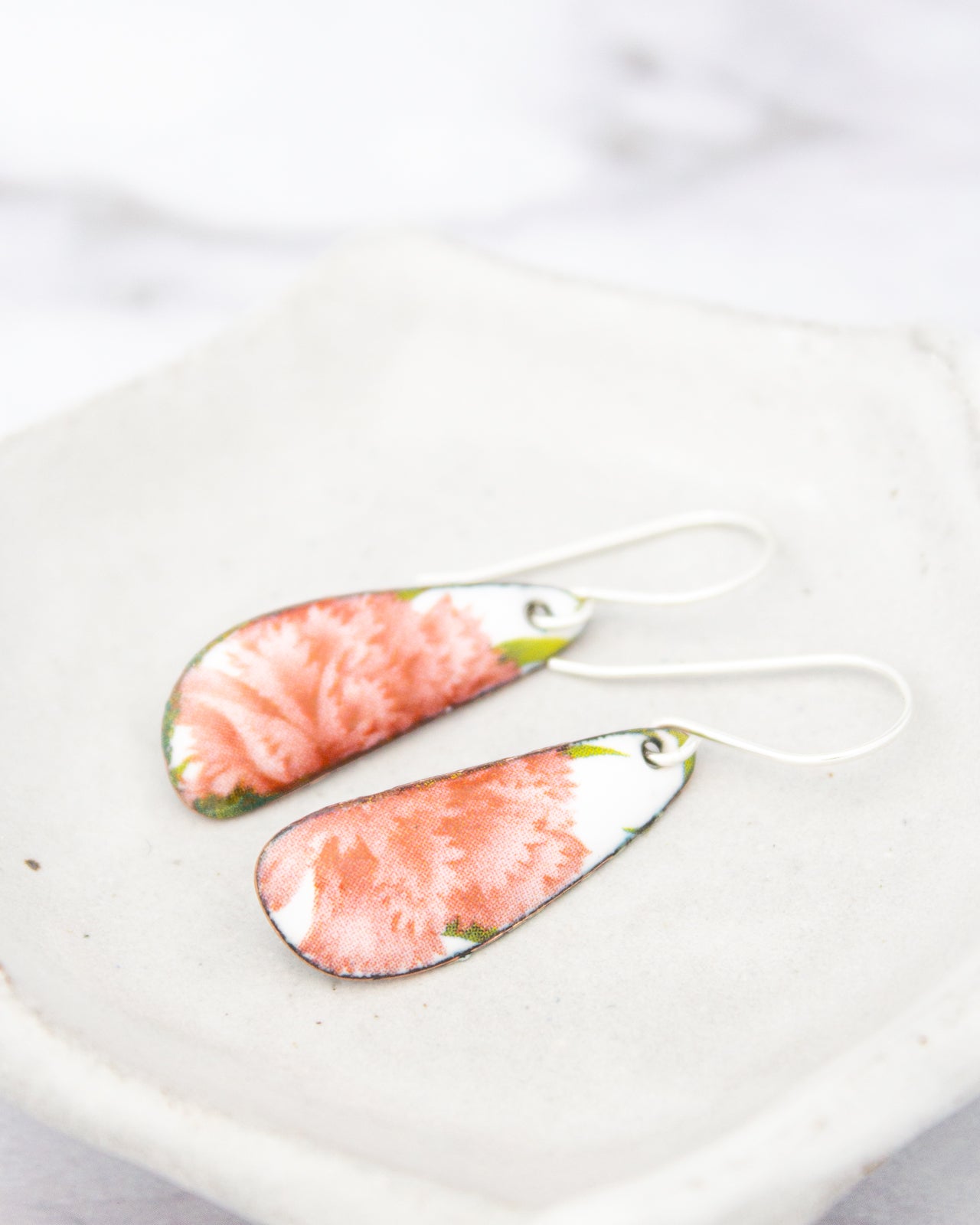 A pair of earrings with a floral design, featuring a combination of pink and green colors.