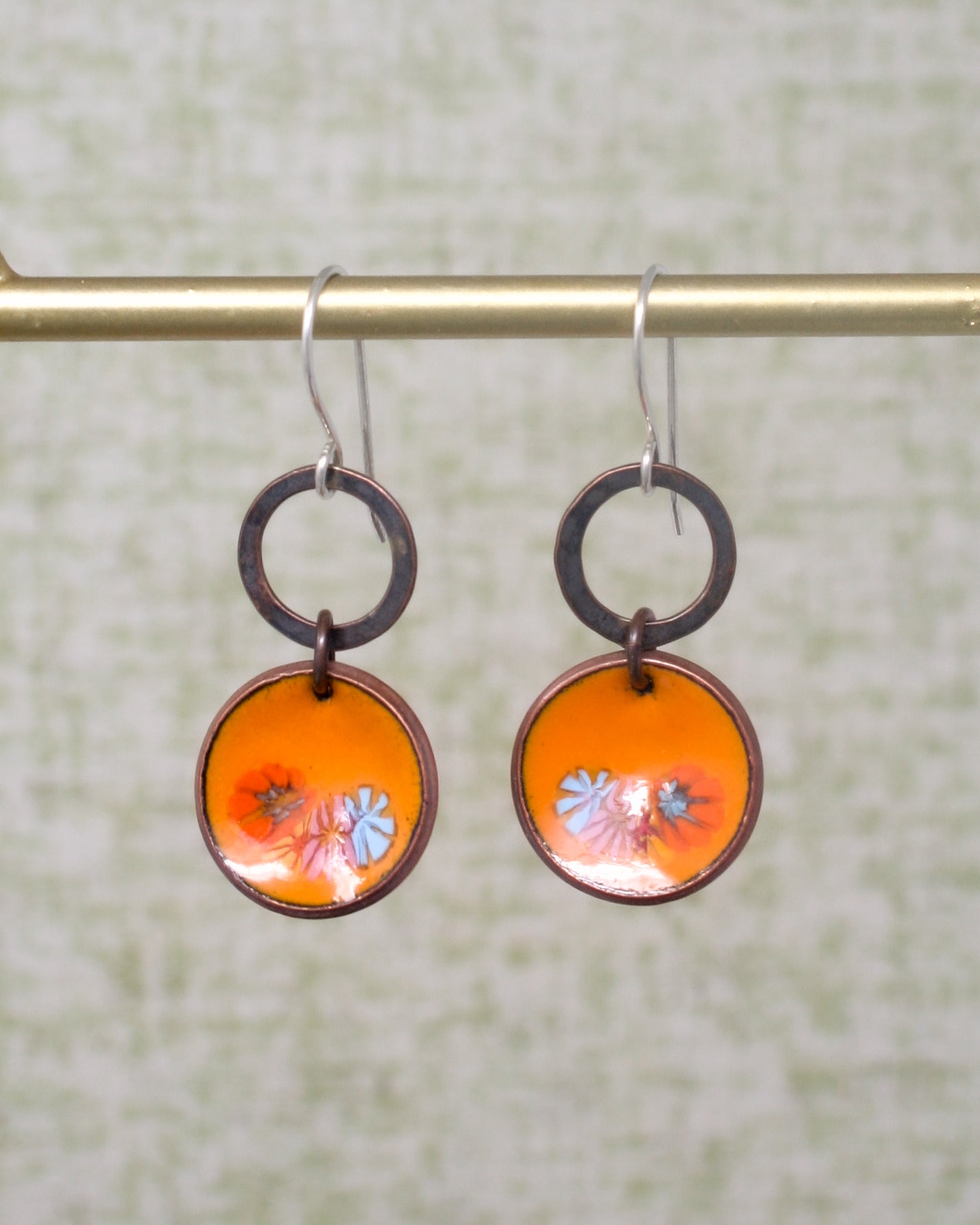 a pair of orange and blue earrings hanging from a hook