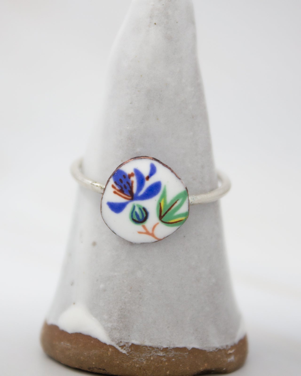 A ring with a floral design on it, placed on a white pedestal.