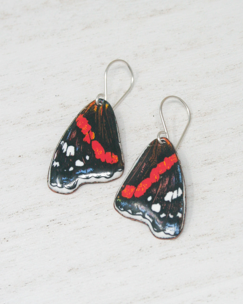 a pair of red and black butterfly shaped earrings