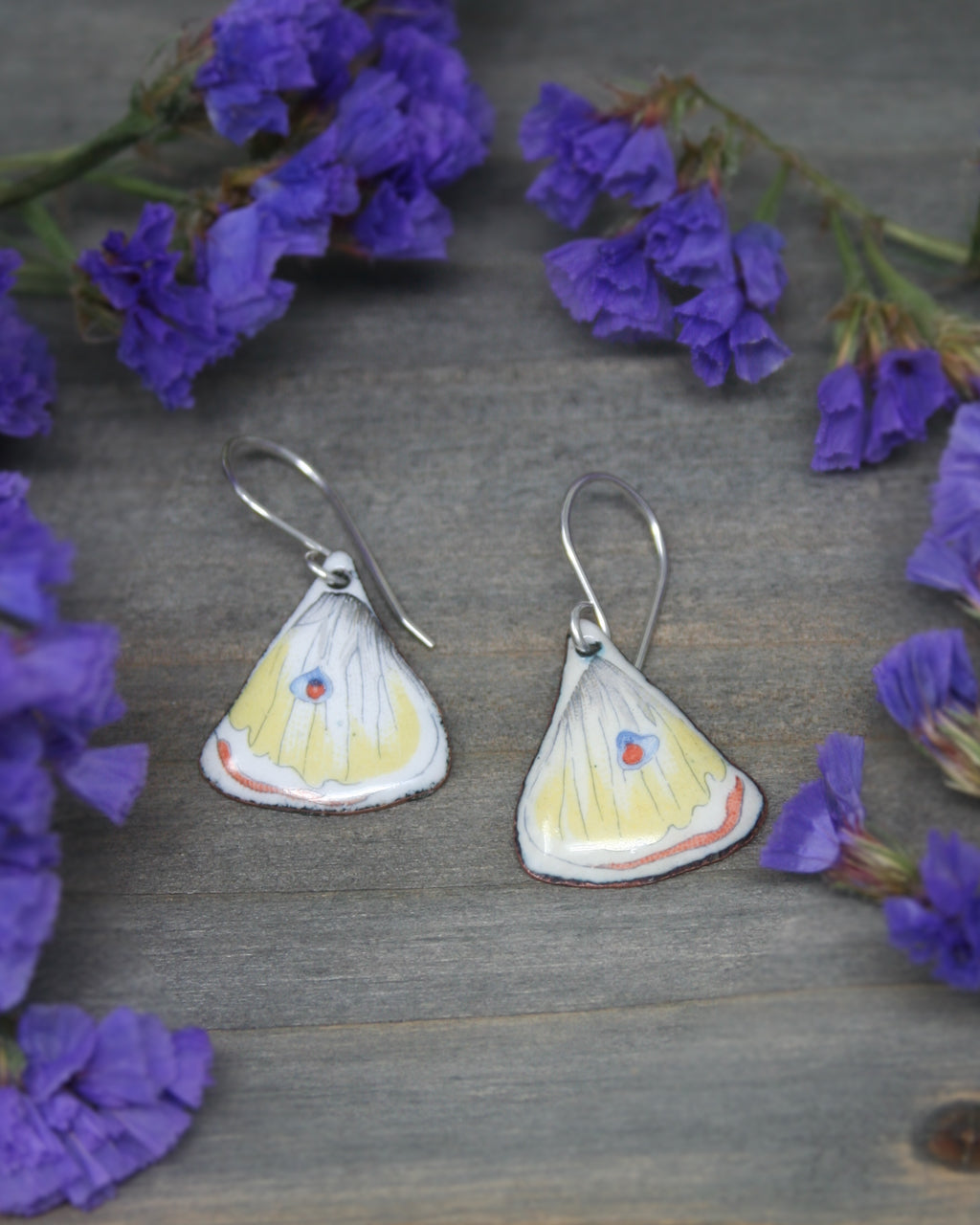 a pair of yellow and white butterfly shaped earrings