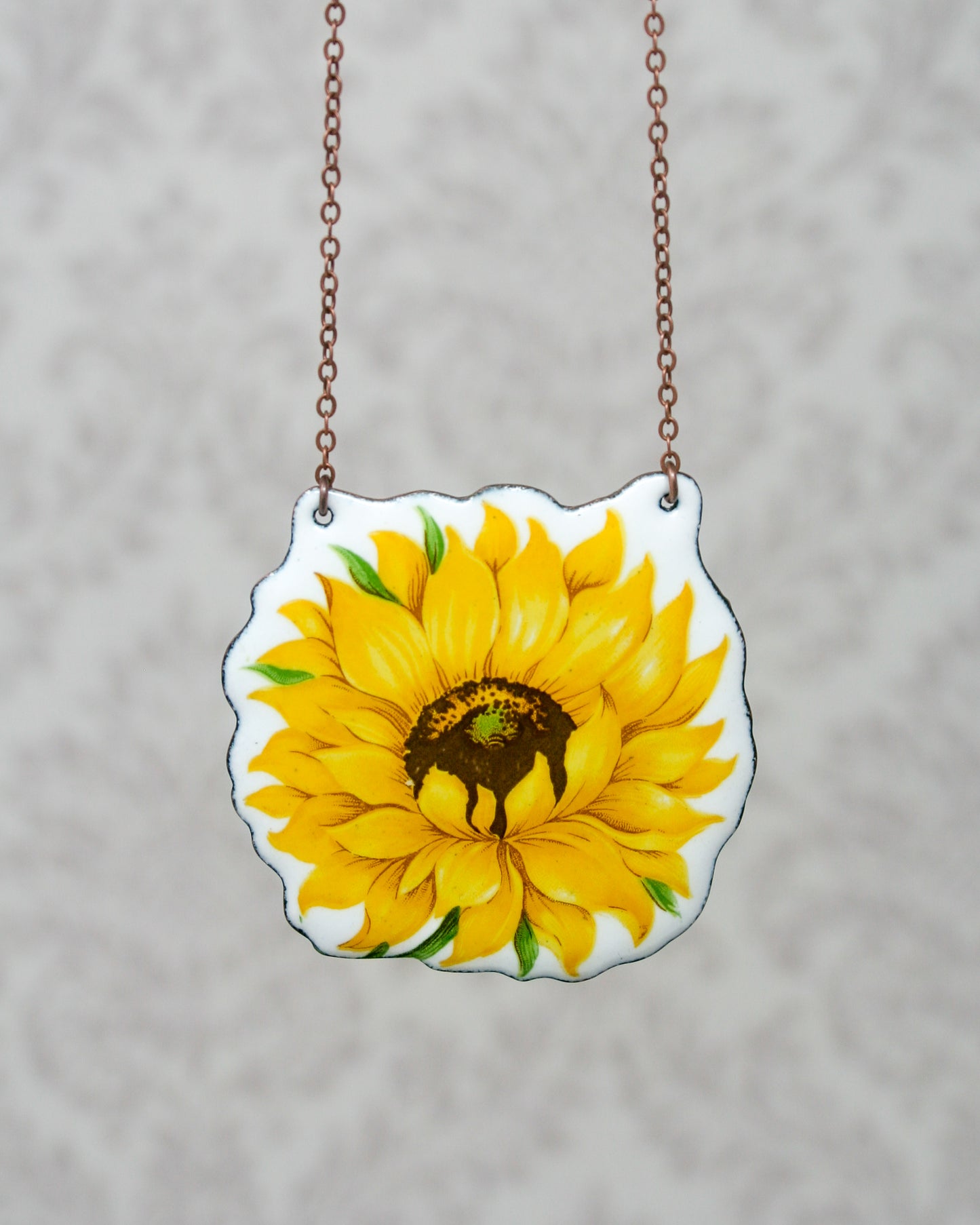 a sunflower painted on a piece of glass hanging from a chain