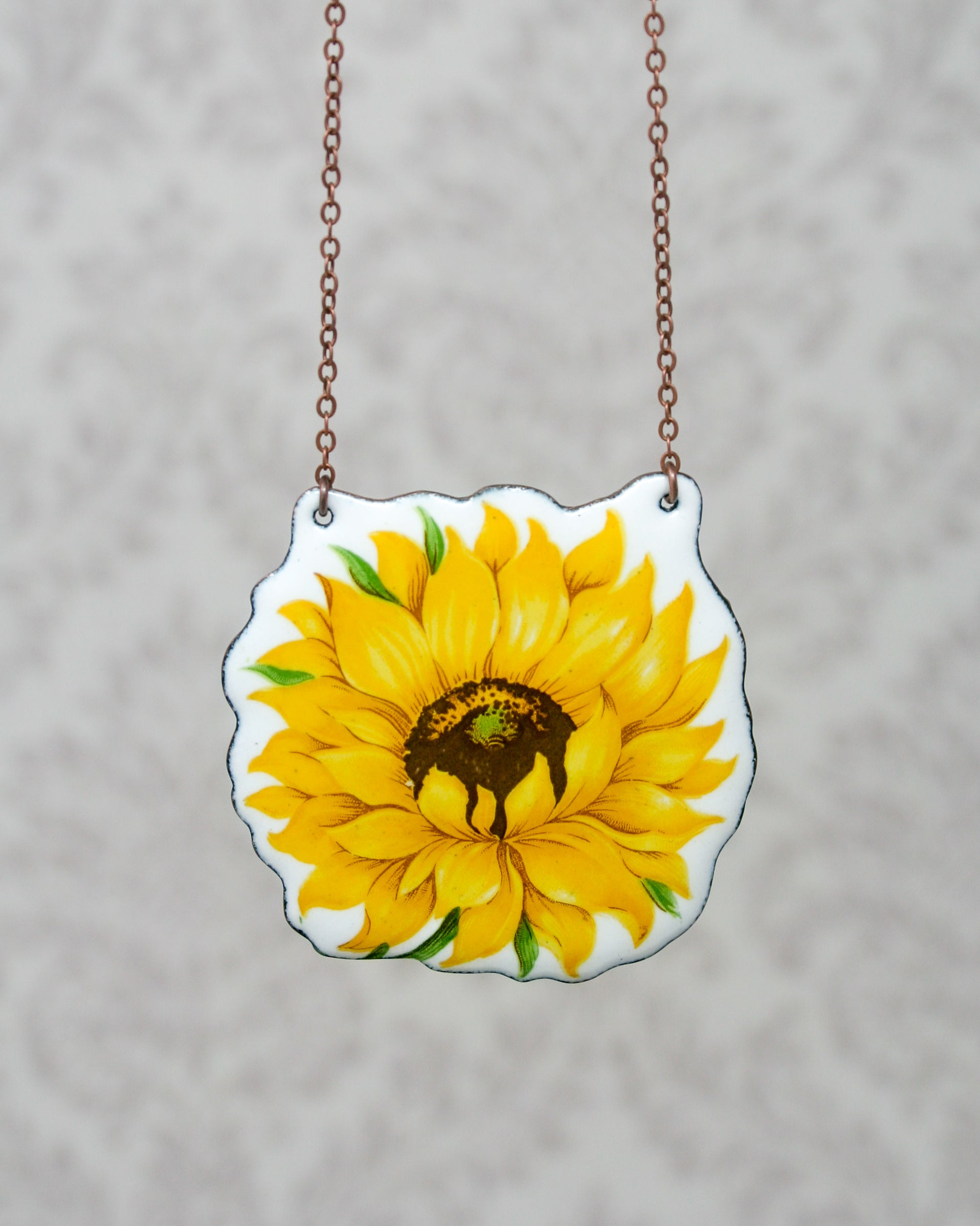 a sunflower painted on a piece of glass hanging from a chain