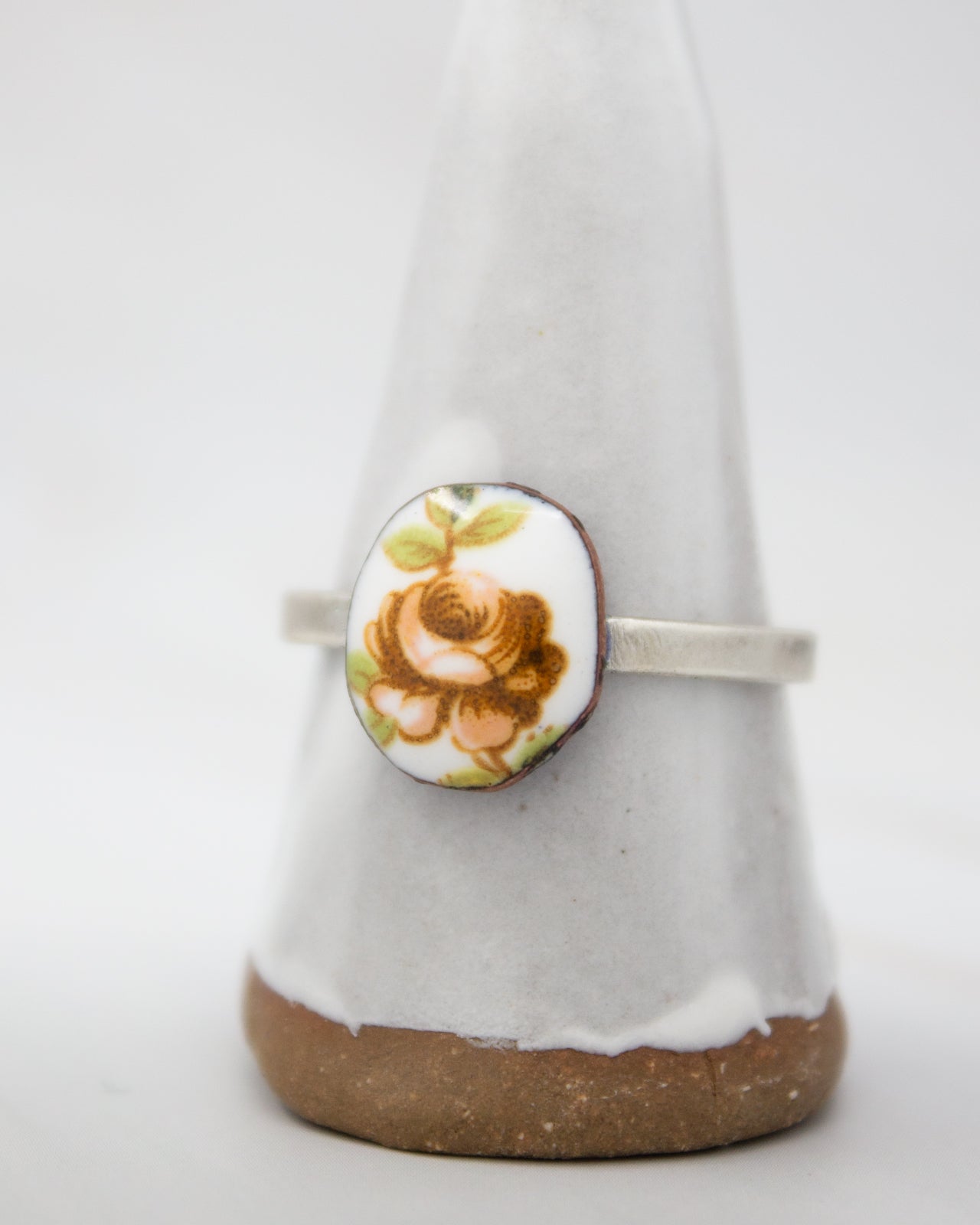 A white ceramic ring stand with a floral design on it.