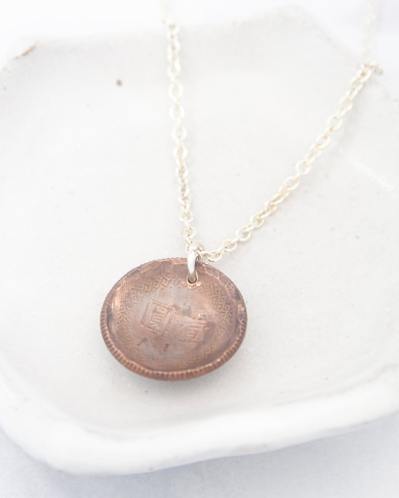 A necklace with a round pendant featuring an engraved design.