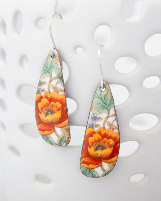 A pair of earrings with a floral design, featuring vibrant orange and red flowers against a white background.