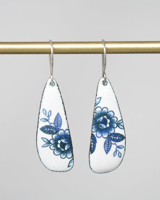 a pair of white and blue earrings hanging from a hook