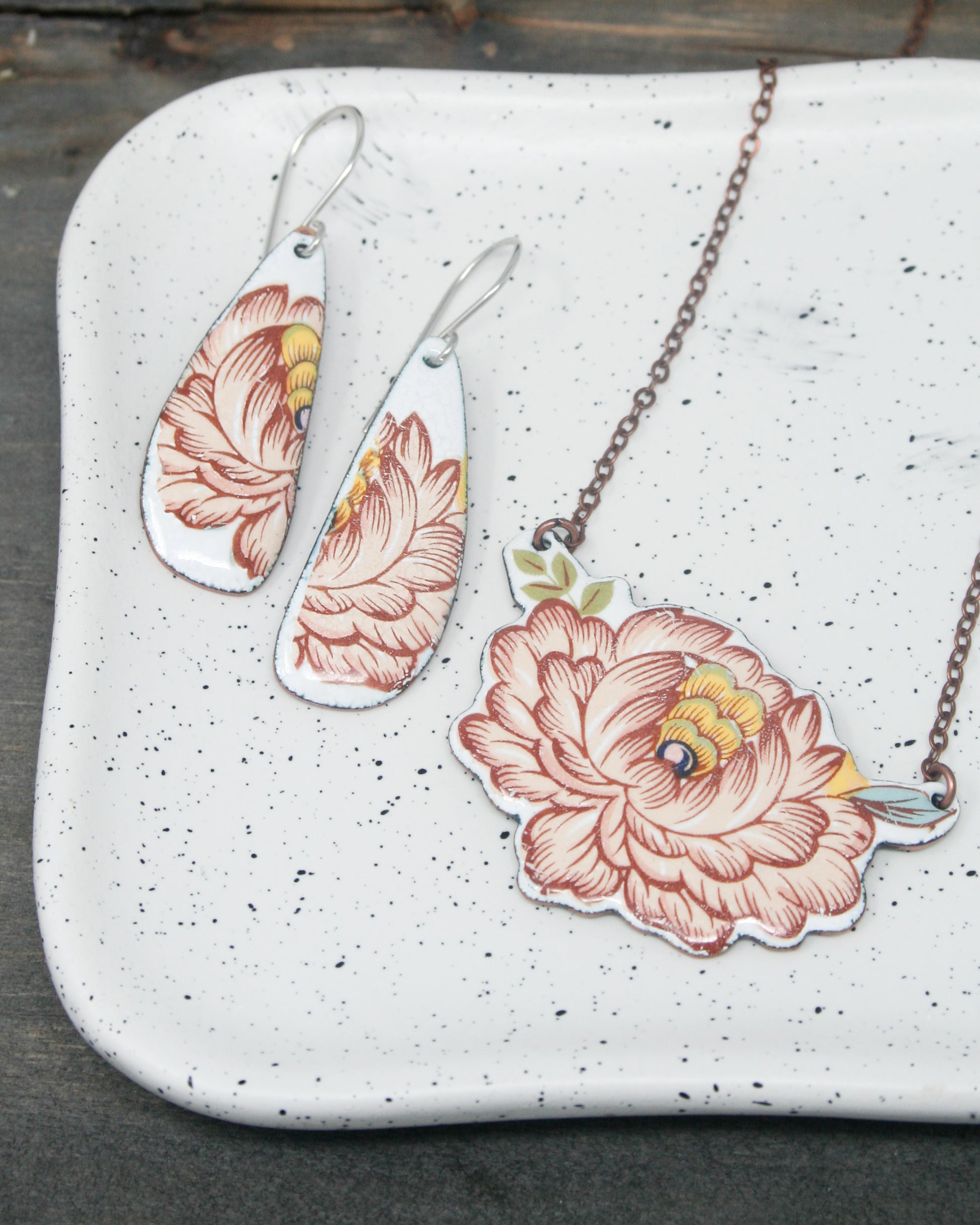 three necklaces with flowers painted on them on a tray