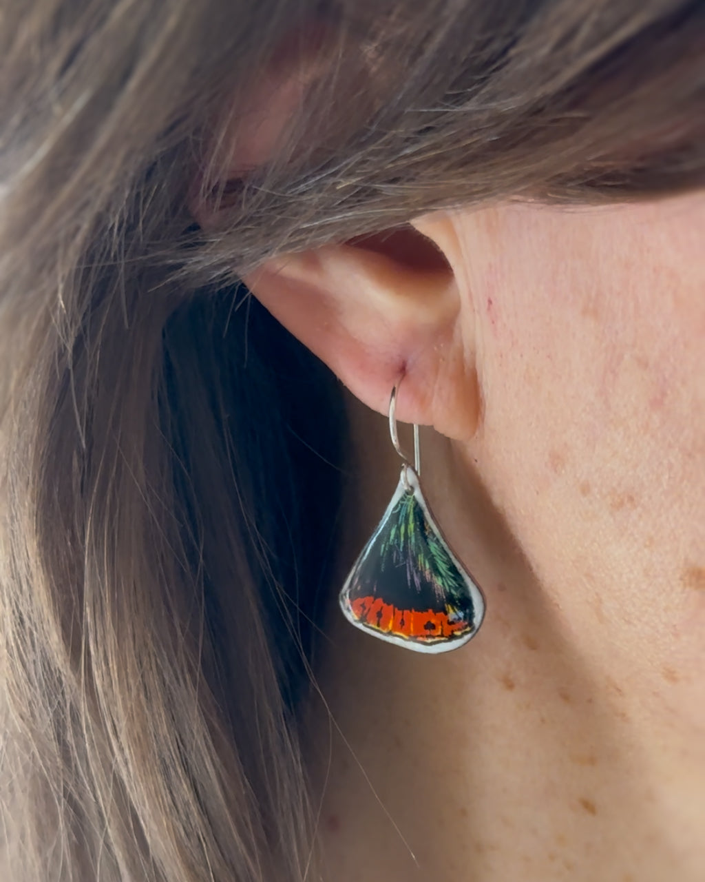 a close up of a person wearing a pair of earrings