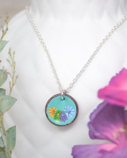 A necklace with a circular pendant featuring a colorful floral design.