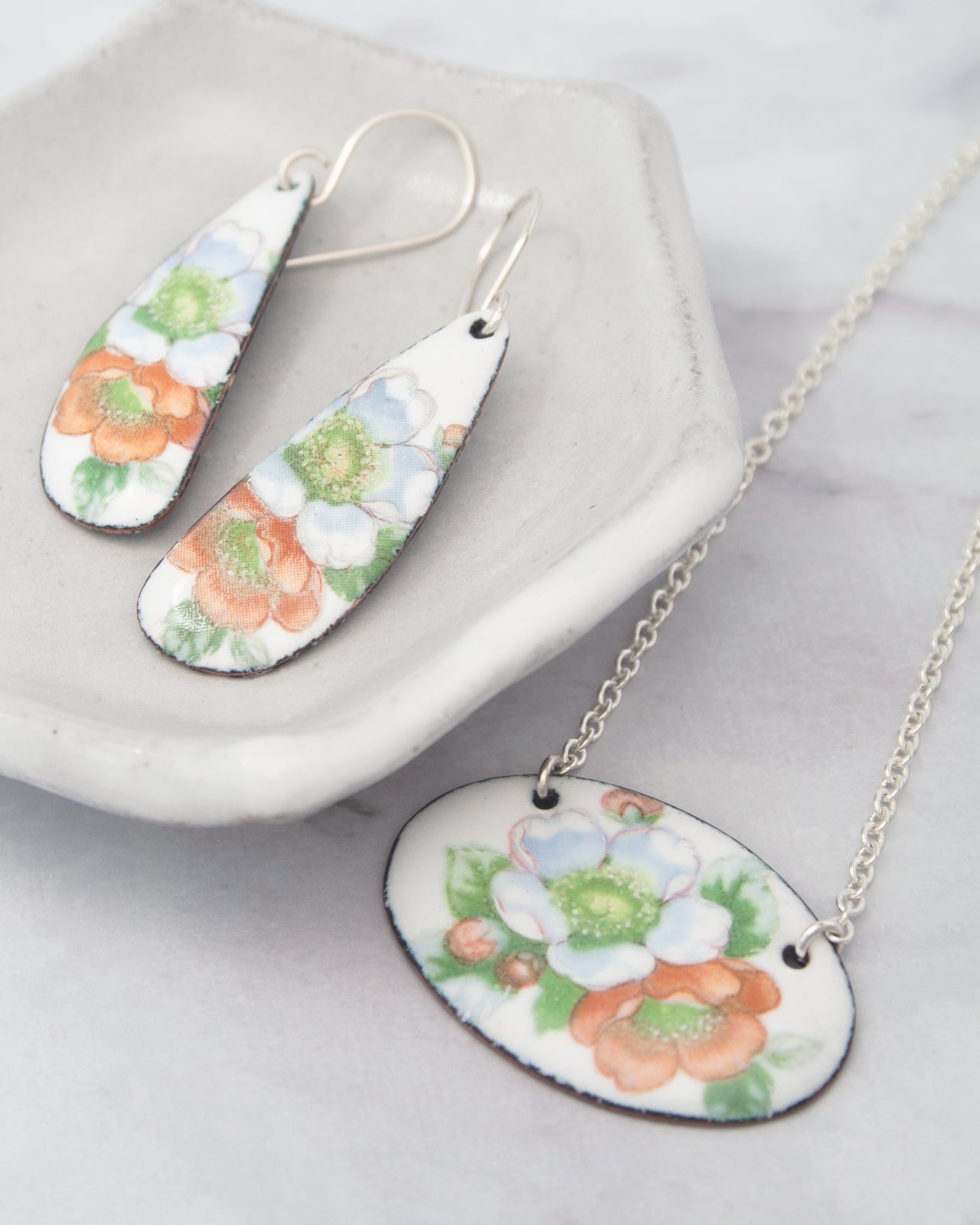 a pair of earrings and a necklace with floral designs.