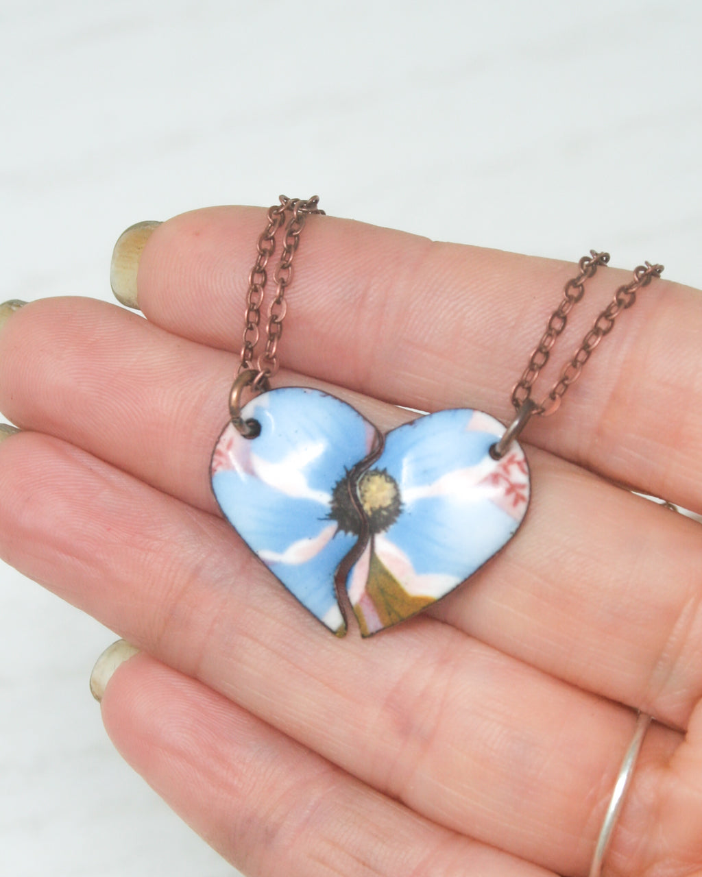 a hand holding a blue heart shaped pendant