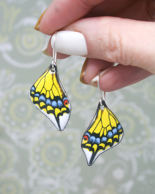 a hand holding a pair of yellow and blue earrings