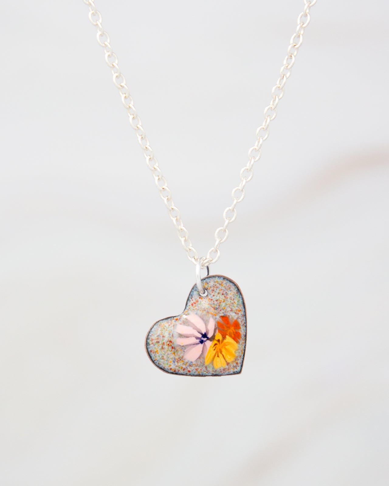 A heart-shaped pendant necklace with a colorful floral design.