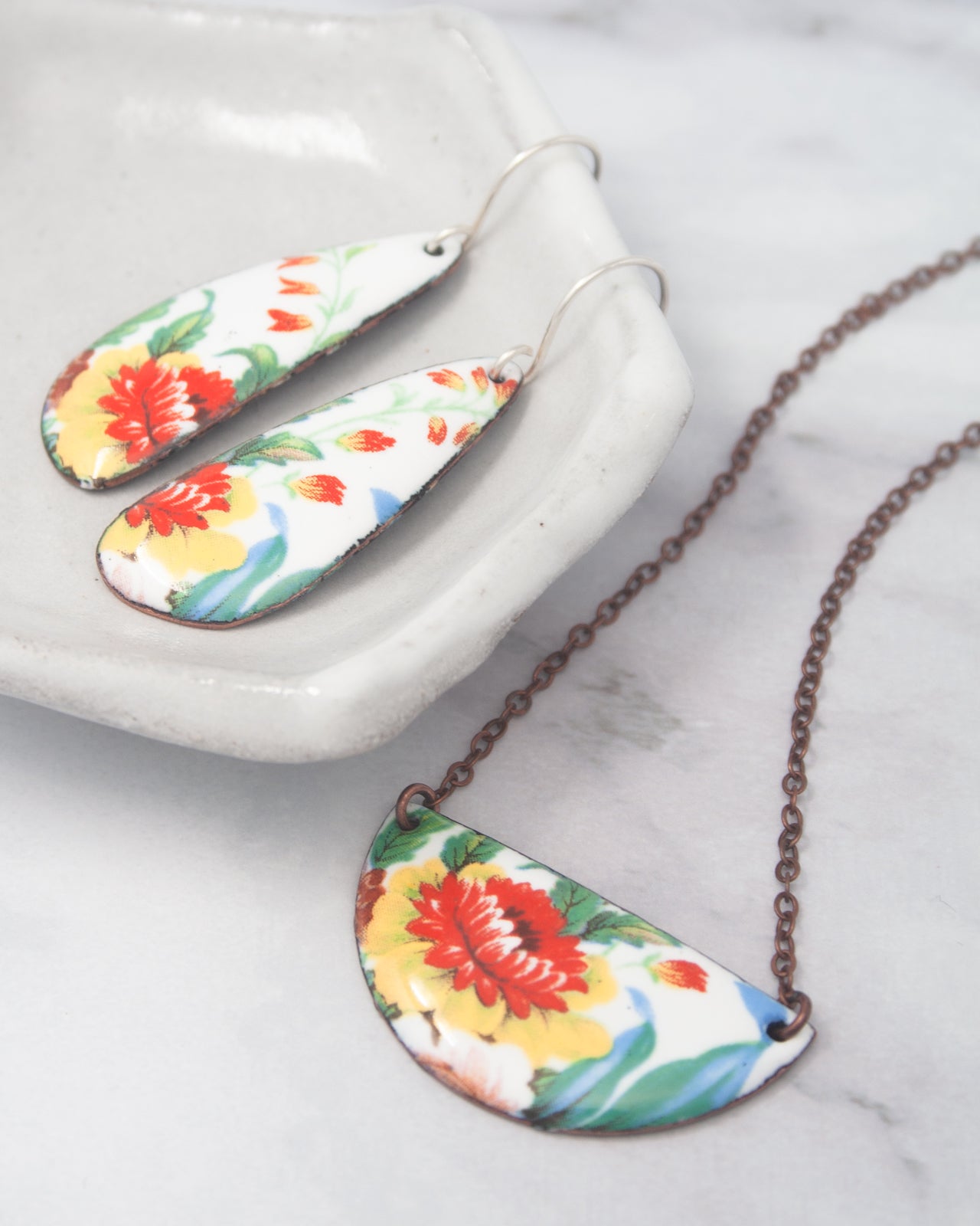 a pair of earrings and a necklace with a floral design.