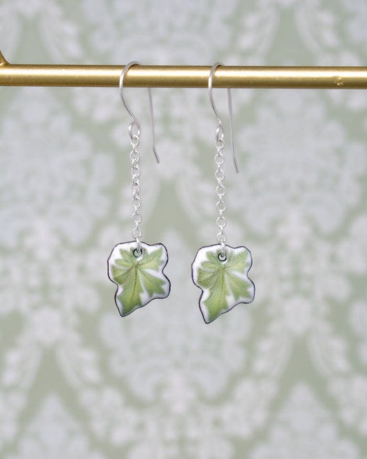 a pair of earrings with a green leaf hanging from it