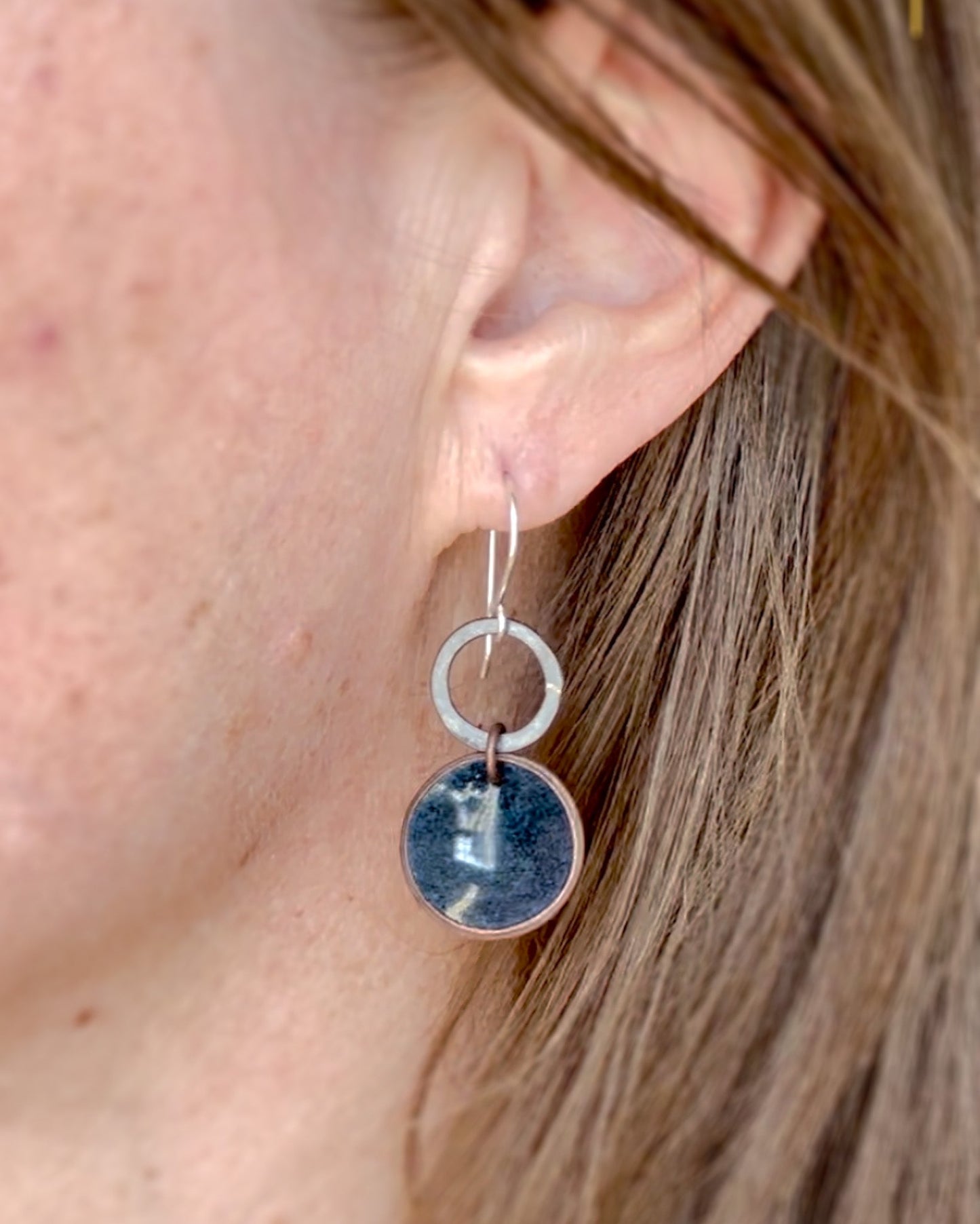 a close up of a person wearing a pair of earrings