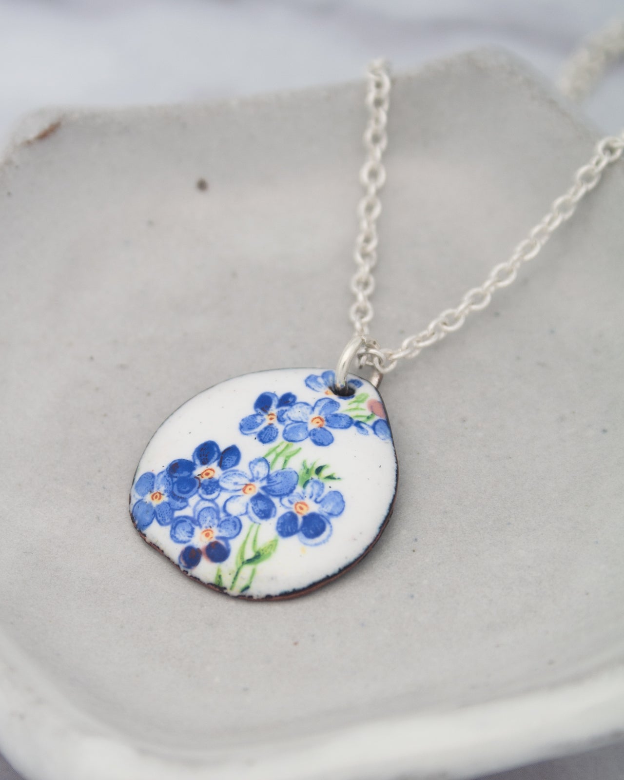 A necklace with a pendant featuring a blue flower design.