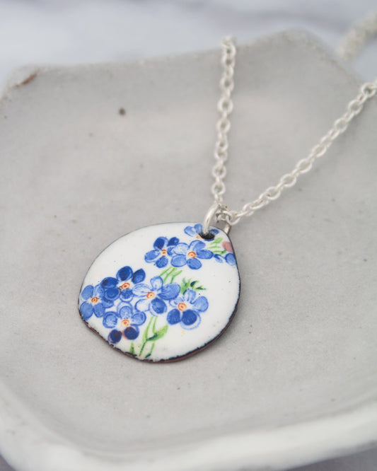 A necklace with a pendant featuring a blue flower design.