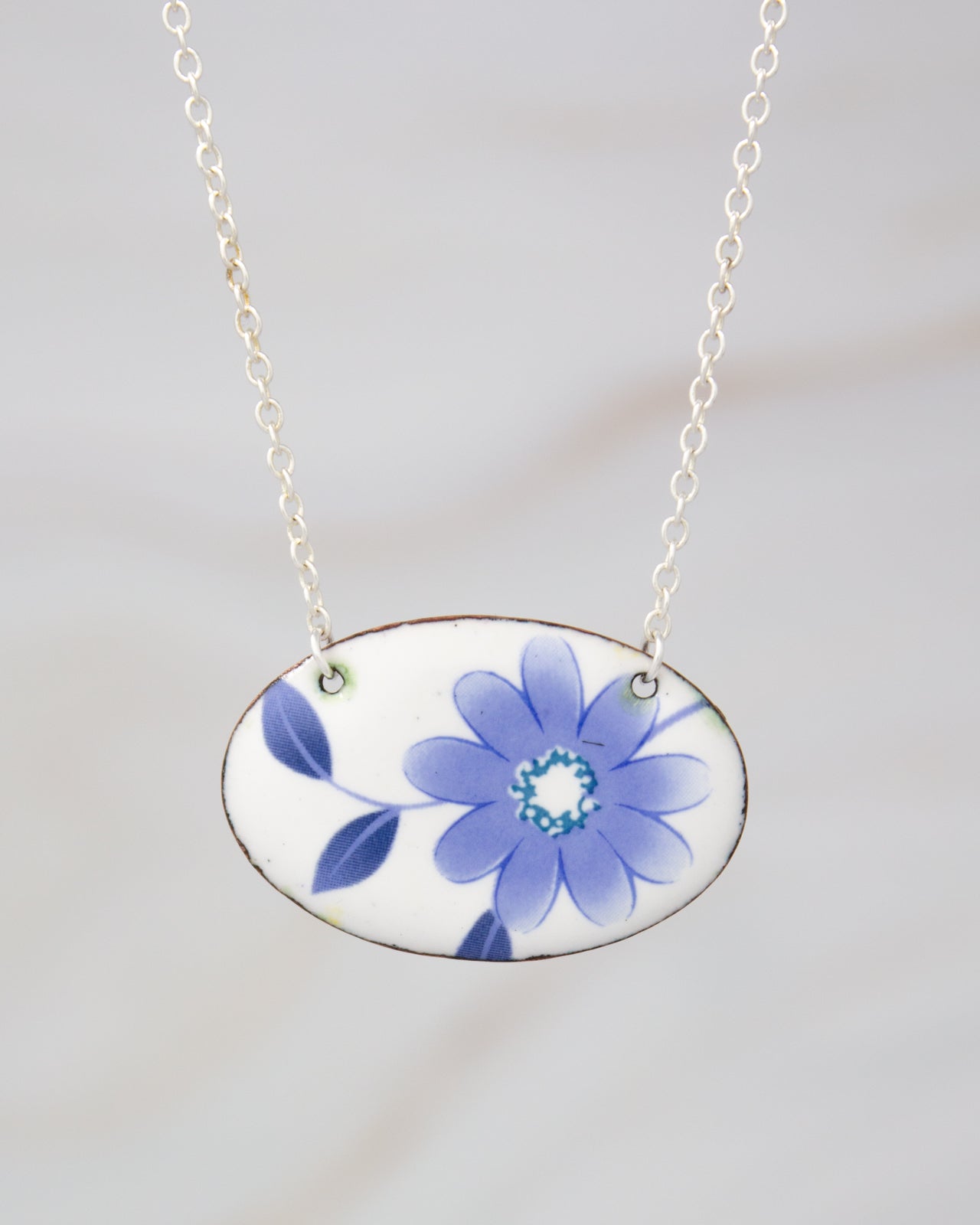 A necklace with a pendant featuring a blue flower design.