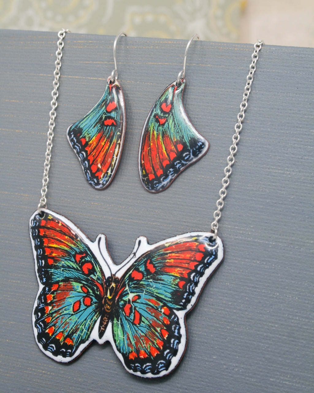 a picture of a butterfly on a necklace and earrings