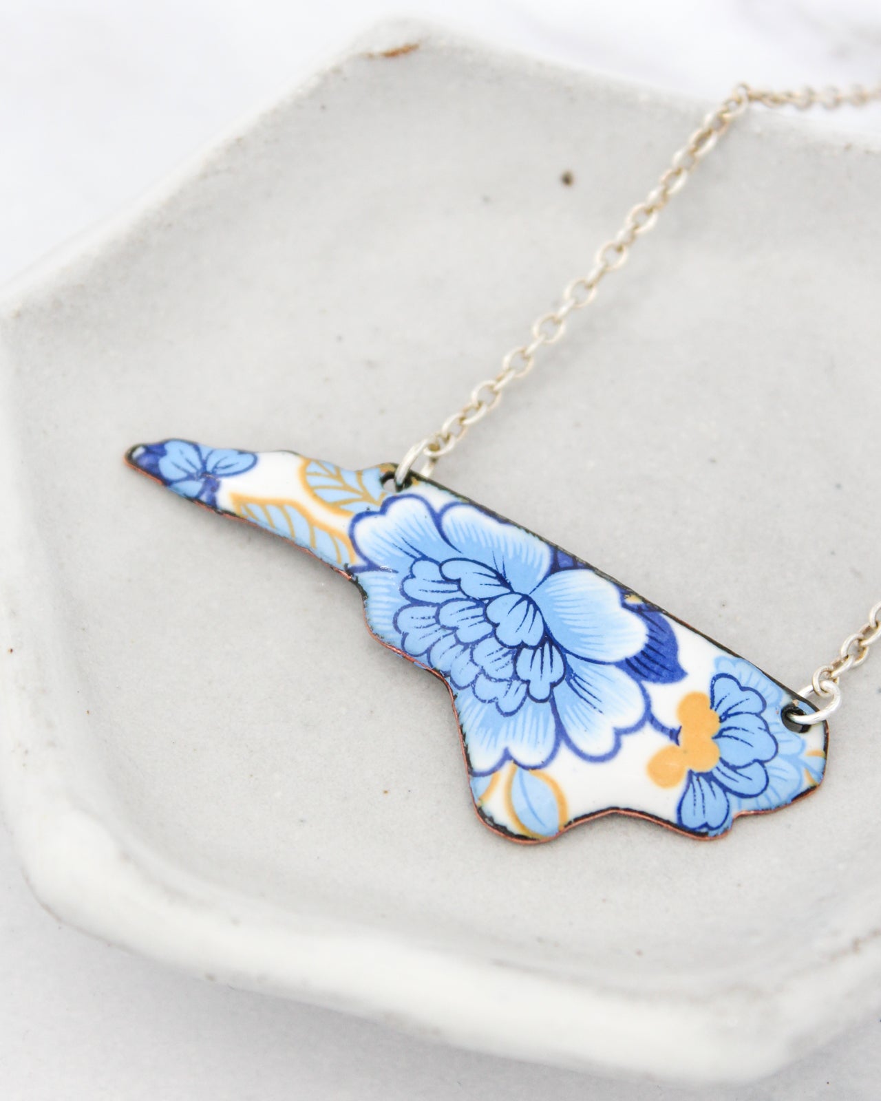 A necklace with a blue and white floral design on a white plate.