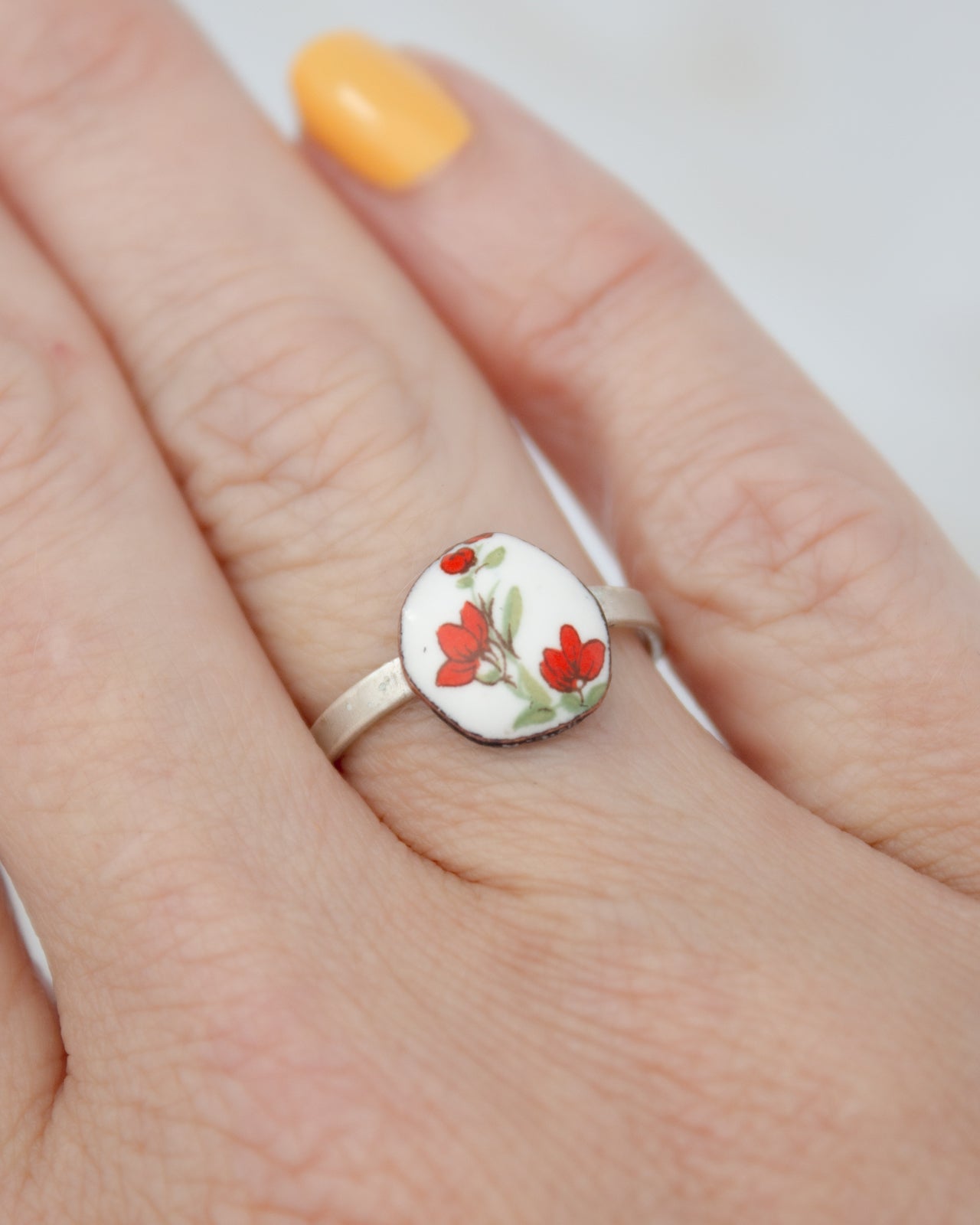 A close-up of a person's hand wearing a ring with a floral design.