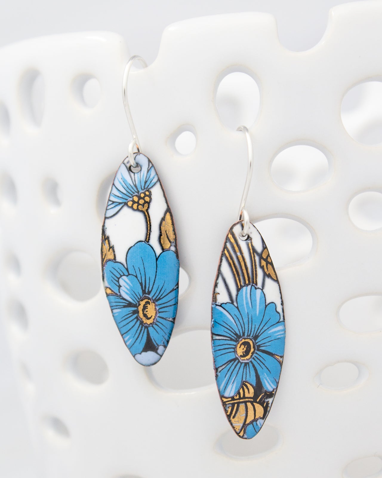 a pair of earrings with blue and gold floral designs.