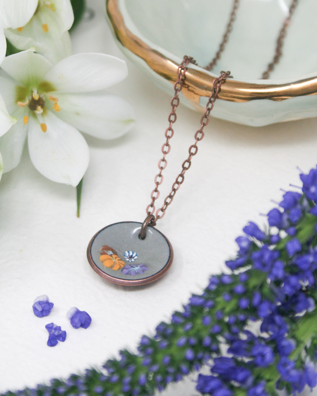 a close up of a necklace on a table with flowers