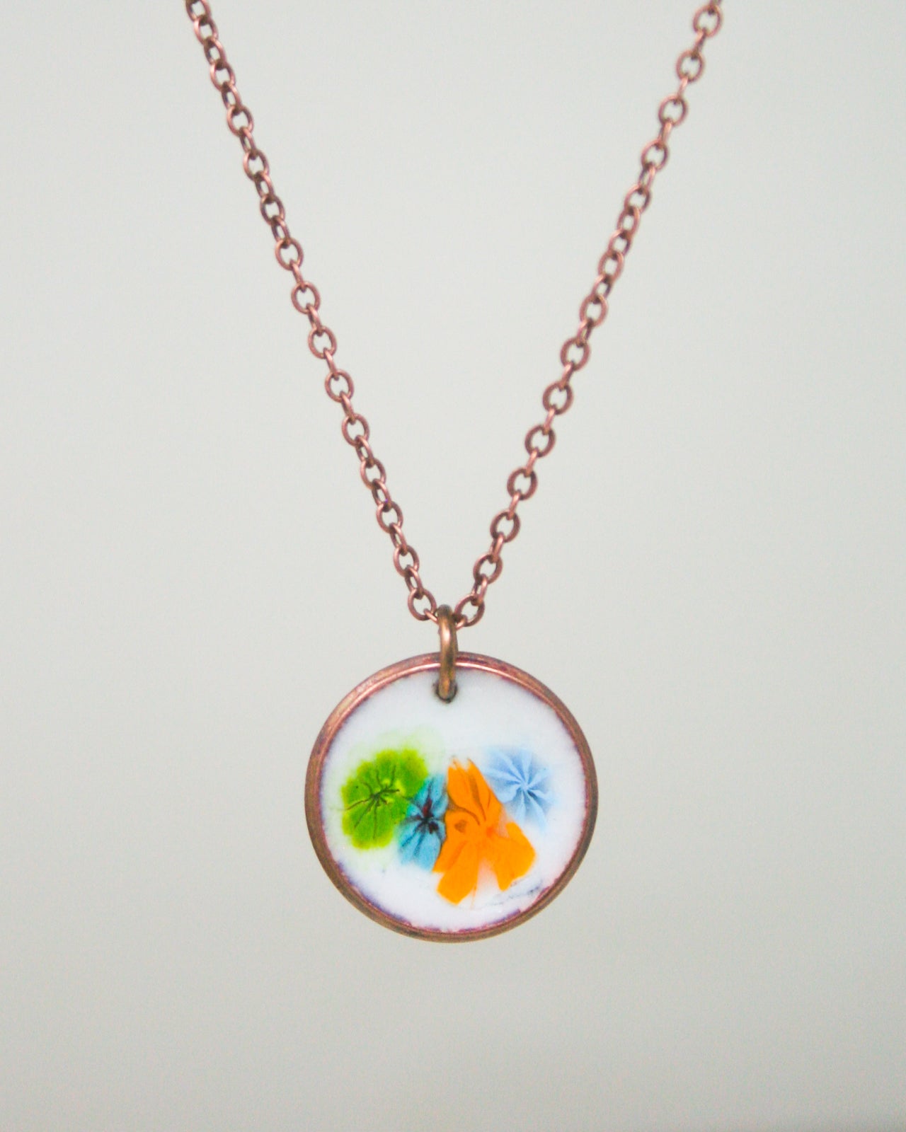 A necklace with a circular pendant featuring a colorful floral design.