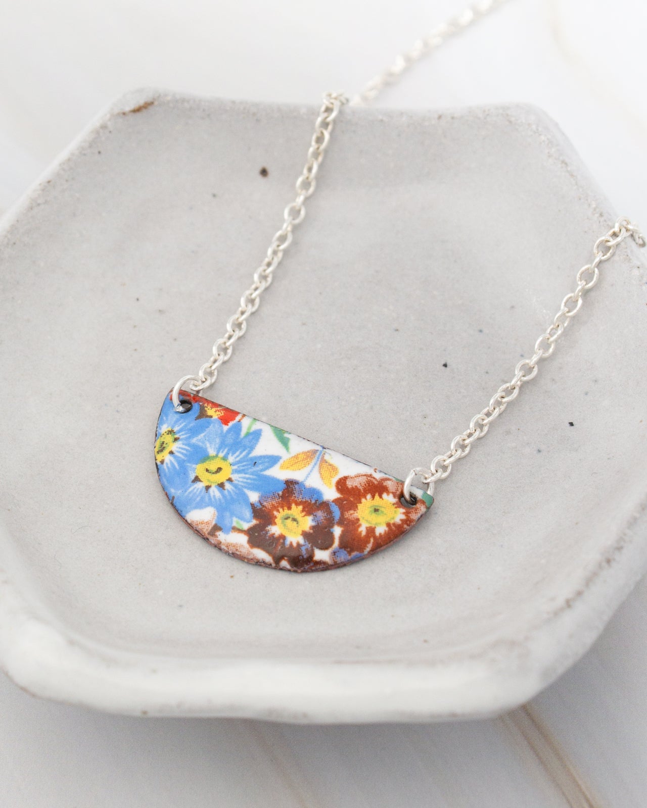 A necklace with a colorful pendant featuring a floral design.