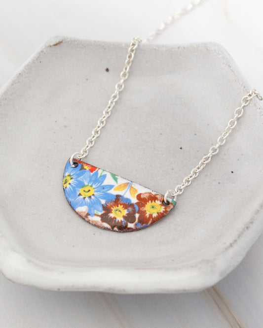 A necklace with a colorful pendant featuring a floral design.