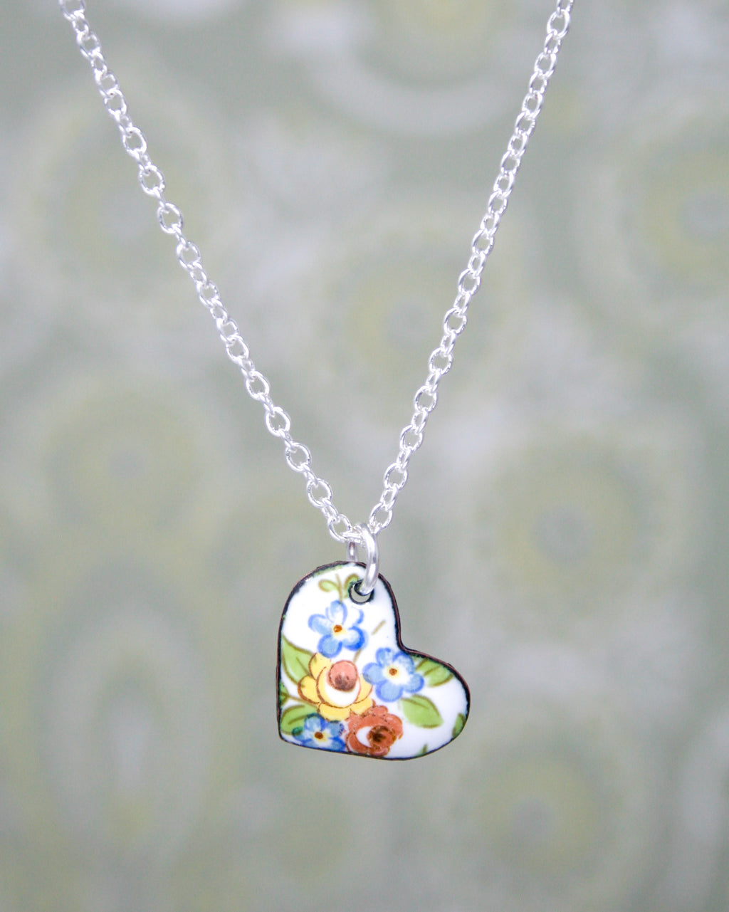 a heart shaped necklace with flowers on it