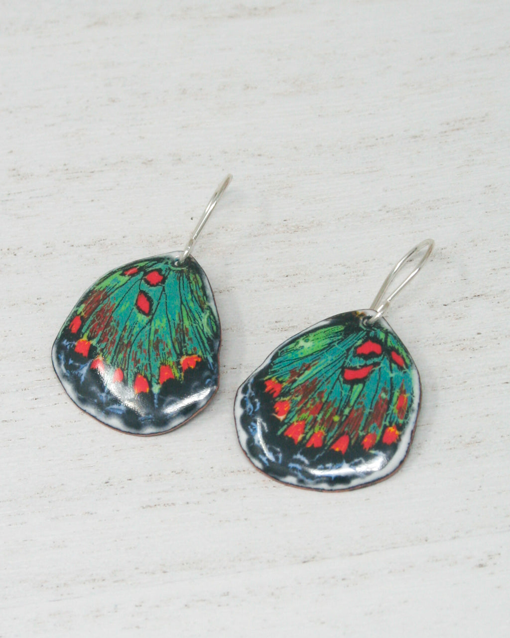 a pair of green and red butterfly earrings