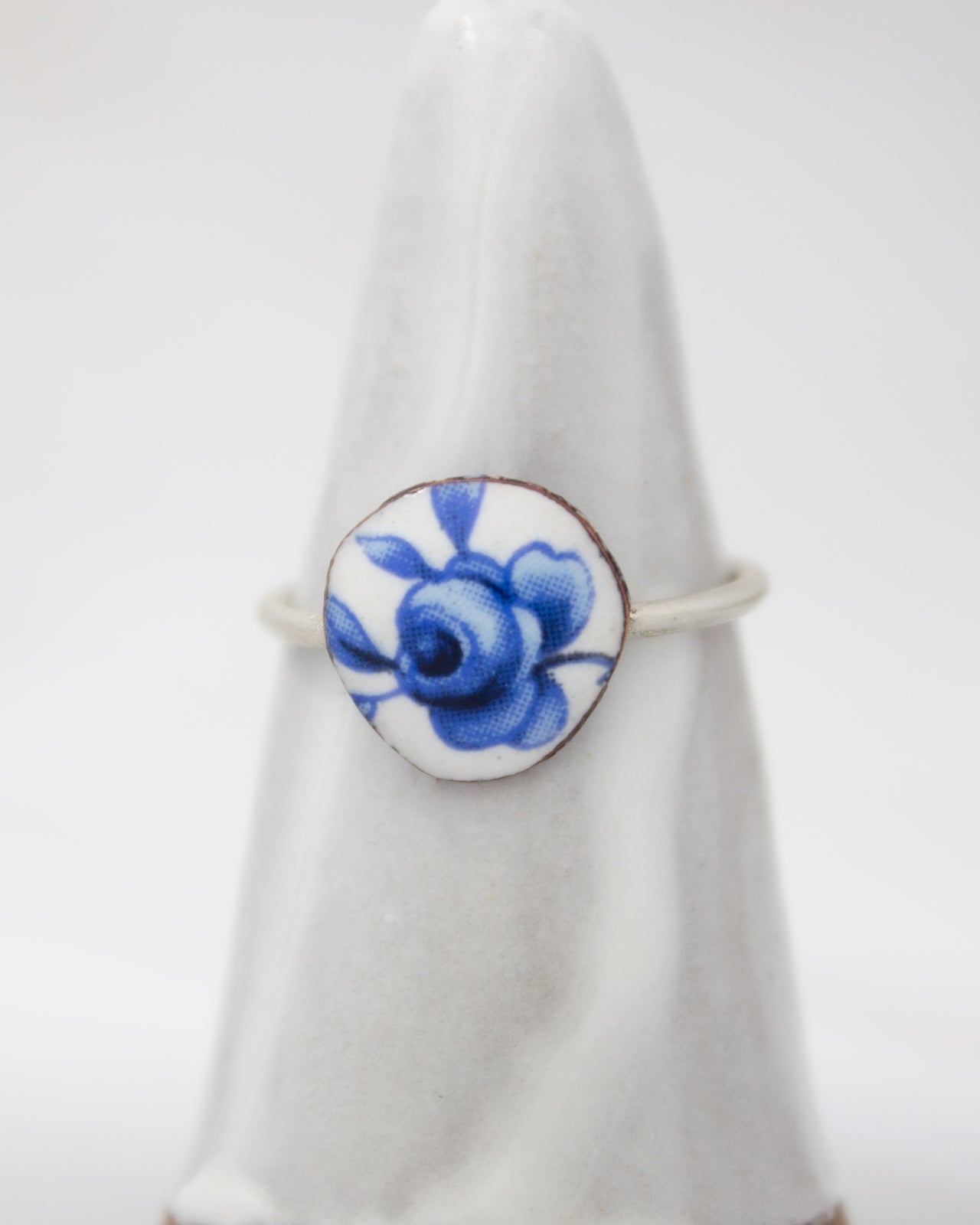 A white ceramic ring with a blue floral design on it.