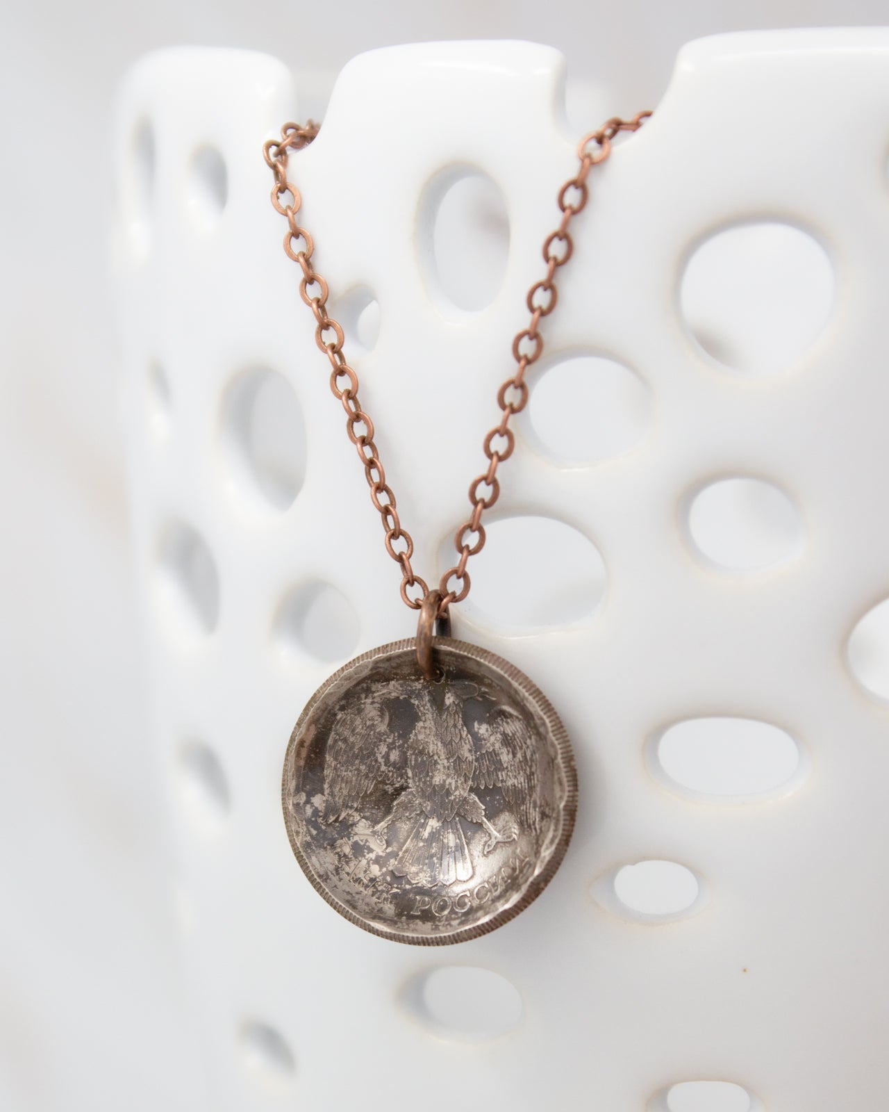 A necklace with a pendant featuring a circular design, hanging from a chain against a white background.