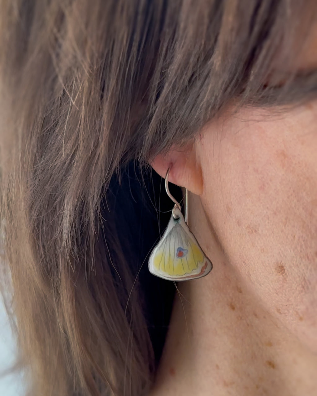 a close up of a person wearing a pair of earrings