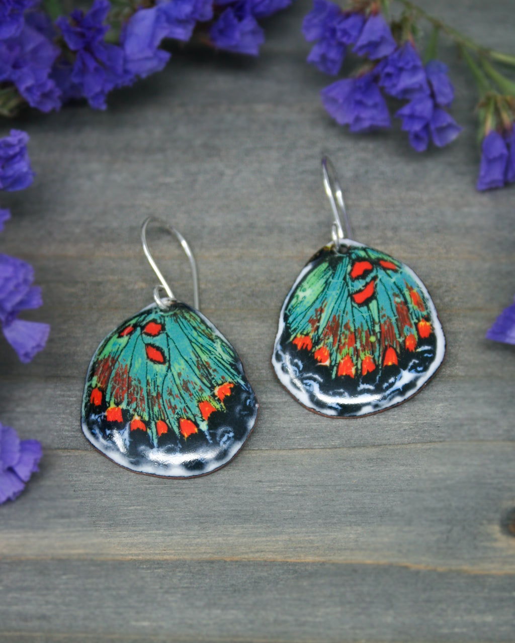 a pair of earrings with a butterfly painted on them