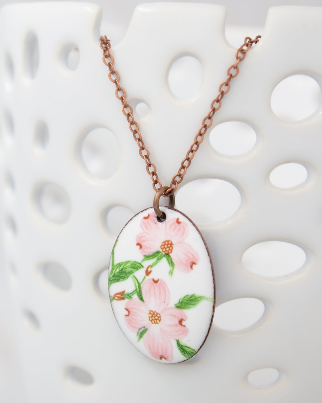 A necklace with a pendant featuring a floral design in pink and green colors.